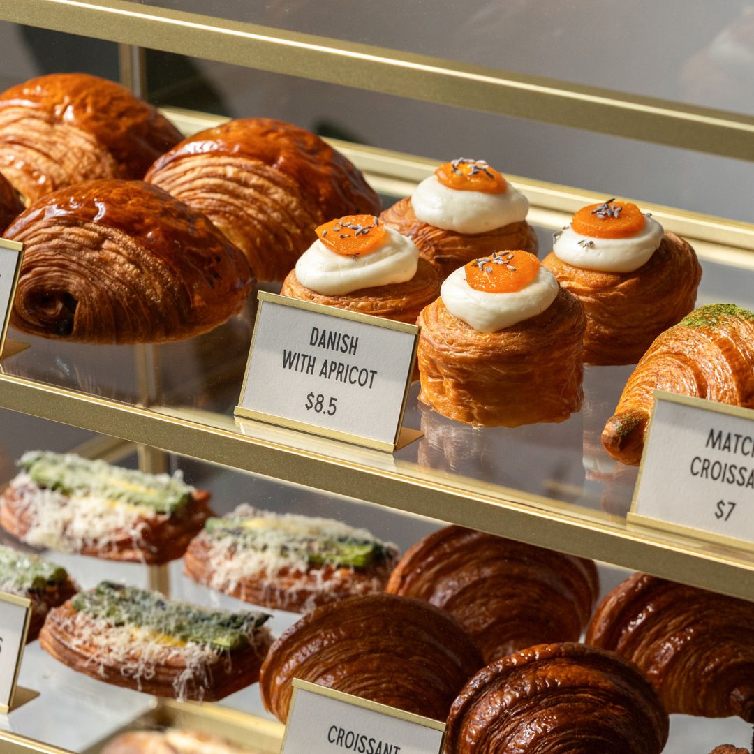 card counter signs in a bakery display case showing pastry pricing