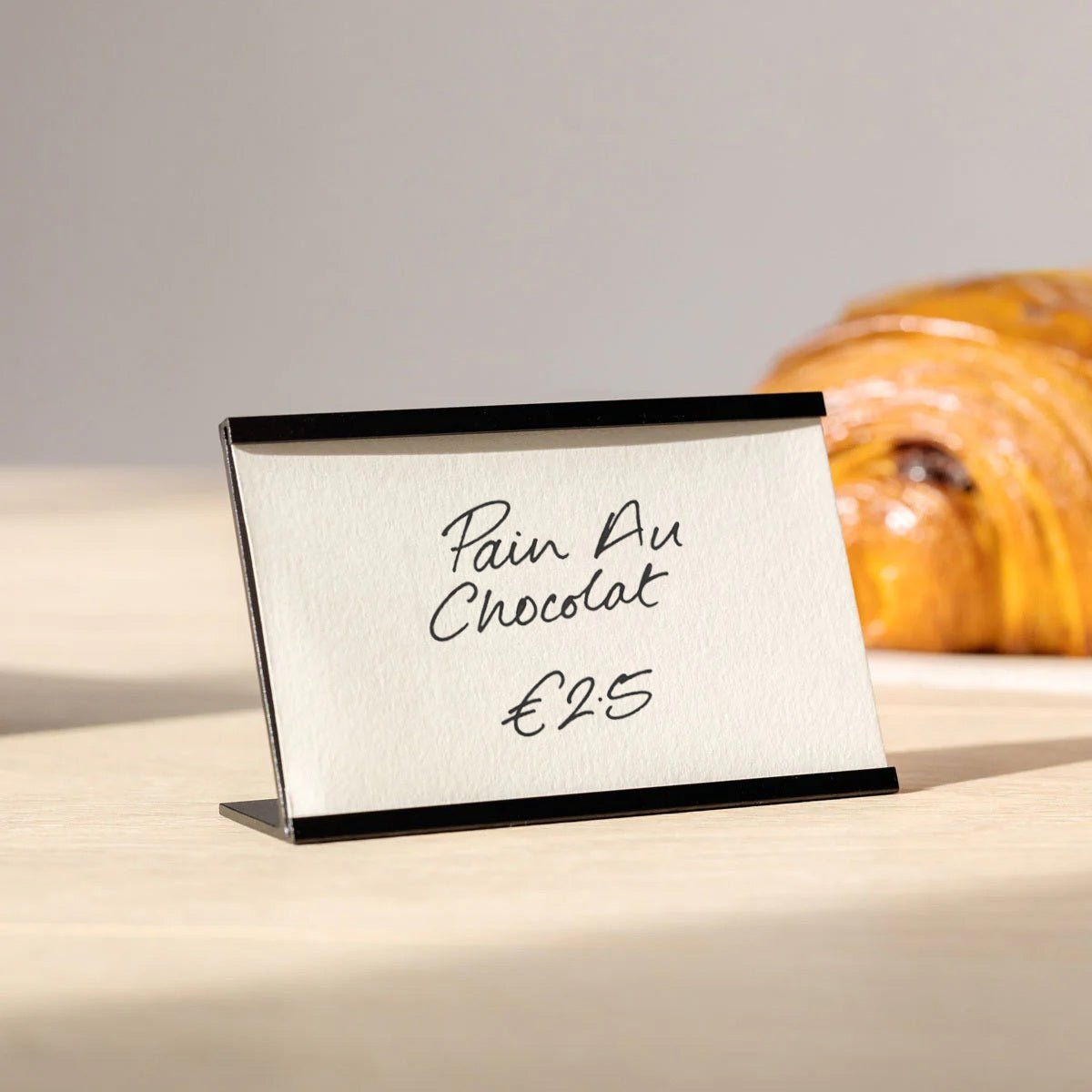 black card counter sign frame with croissant price written and displayed