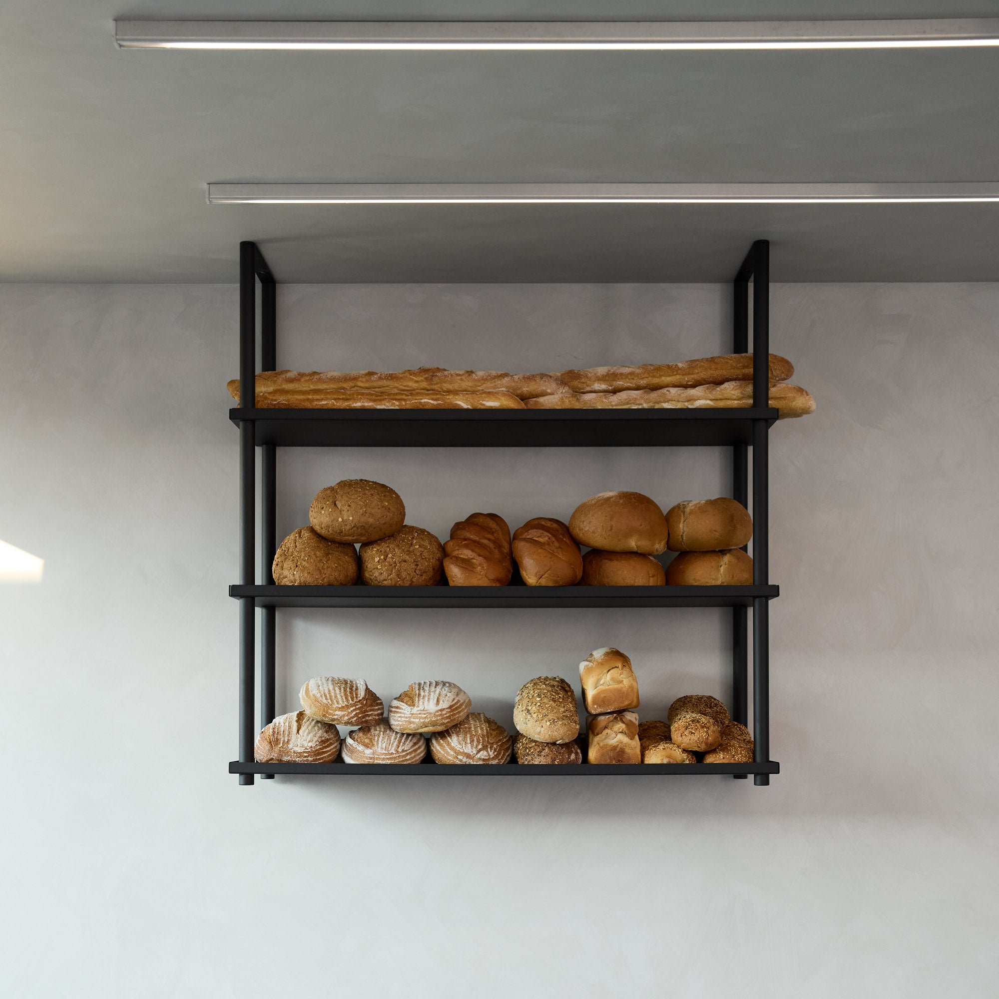 front on photo of black ceiling mounted shelves displaying bread at a bakery