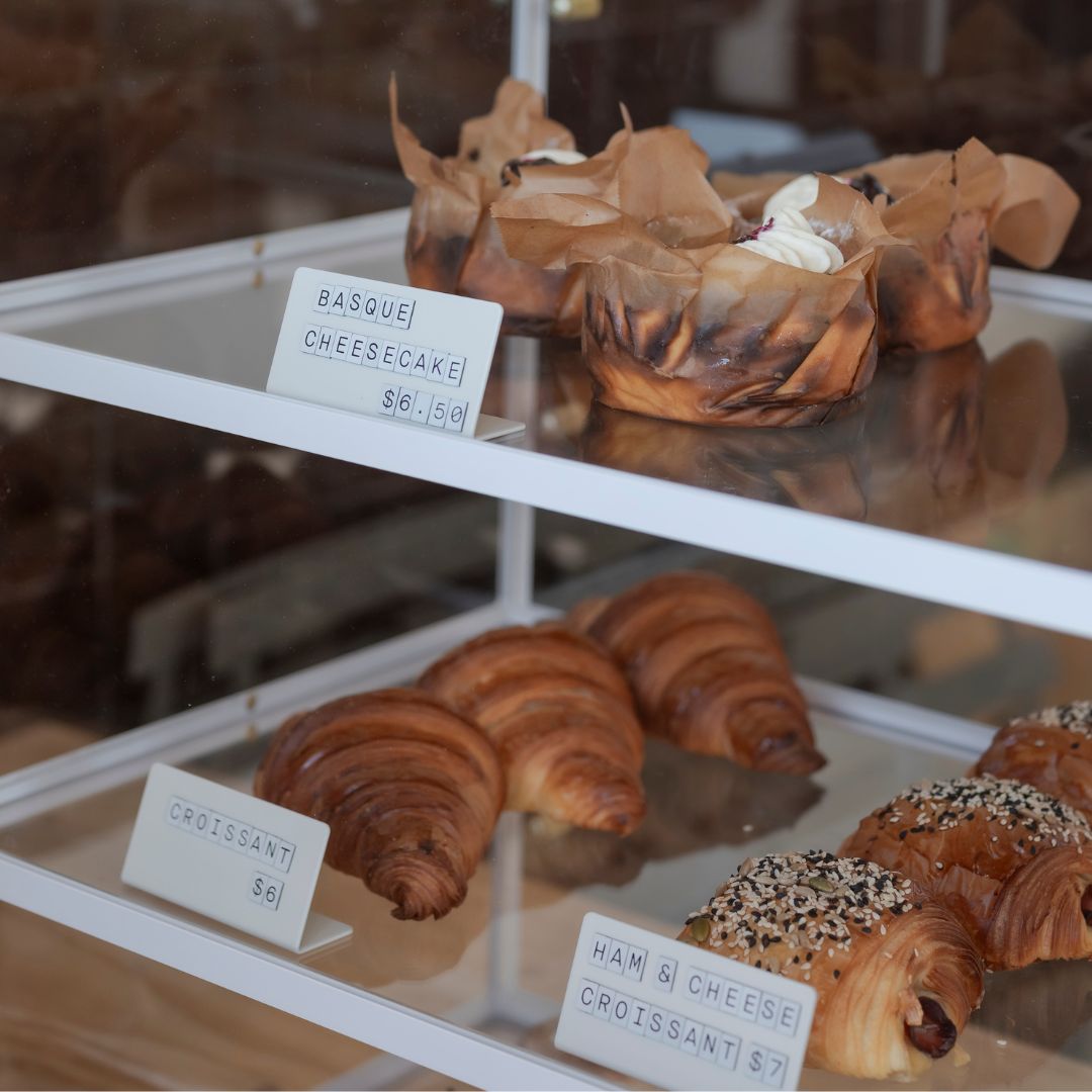 two white shelves storing baked items and small menu signs