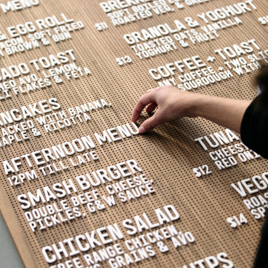 hand adjusting the white peg letter board letters on a wooden peg letter menu