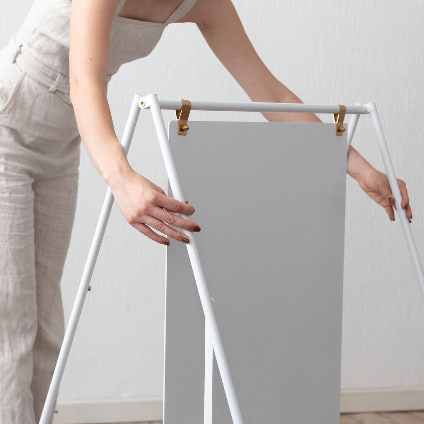 white large sidewalk sign inside a studio with person adjusting the frame