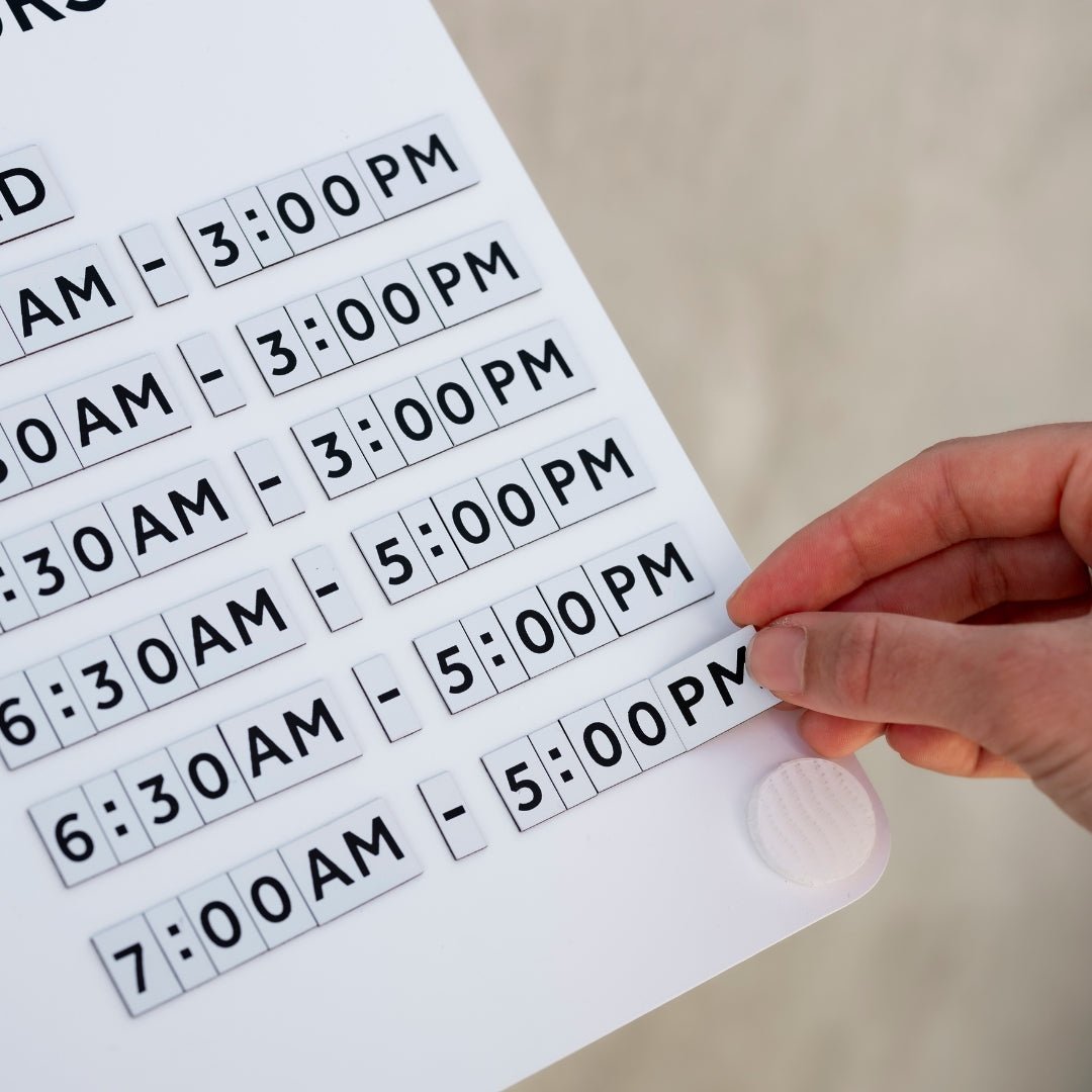 Close-up of magnetic numbers being placed on white Opening Hours advertising Sign with smooth powder-coated surface