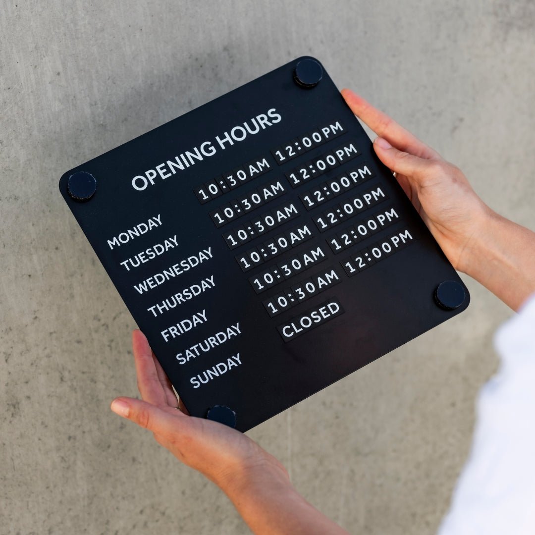 Person holding black open sign for window showing days and times their store is open their store open hours for operation