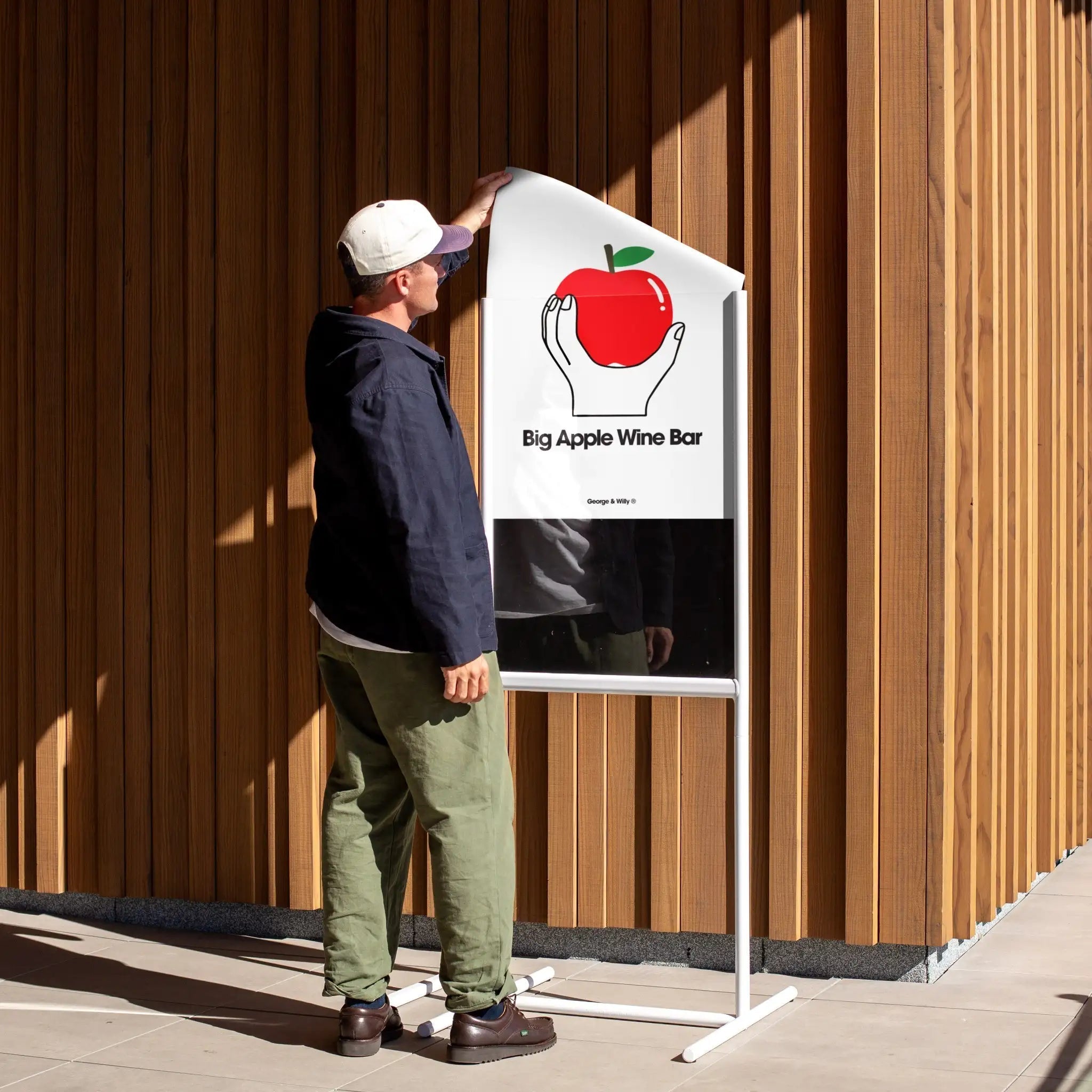 person removing a poster from the tall poster sidewalk metal sign