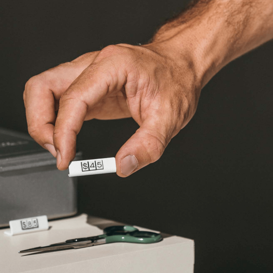 hand picking up a white small pricing tag