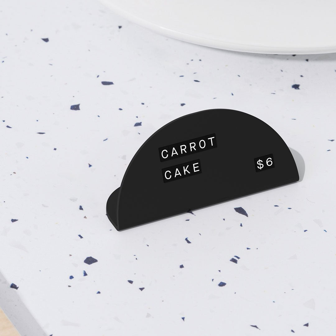 black round counter signs with black tiled magnet letters on a counter top