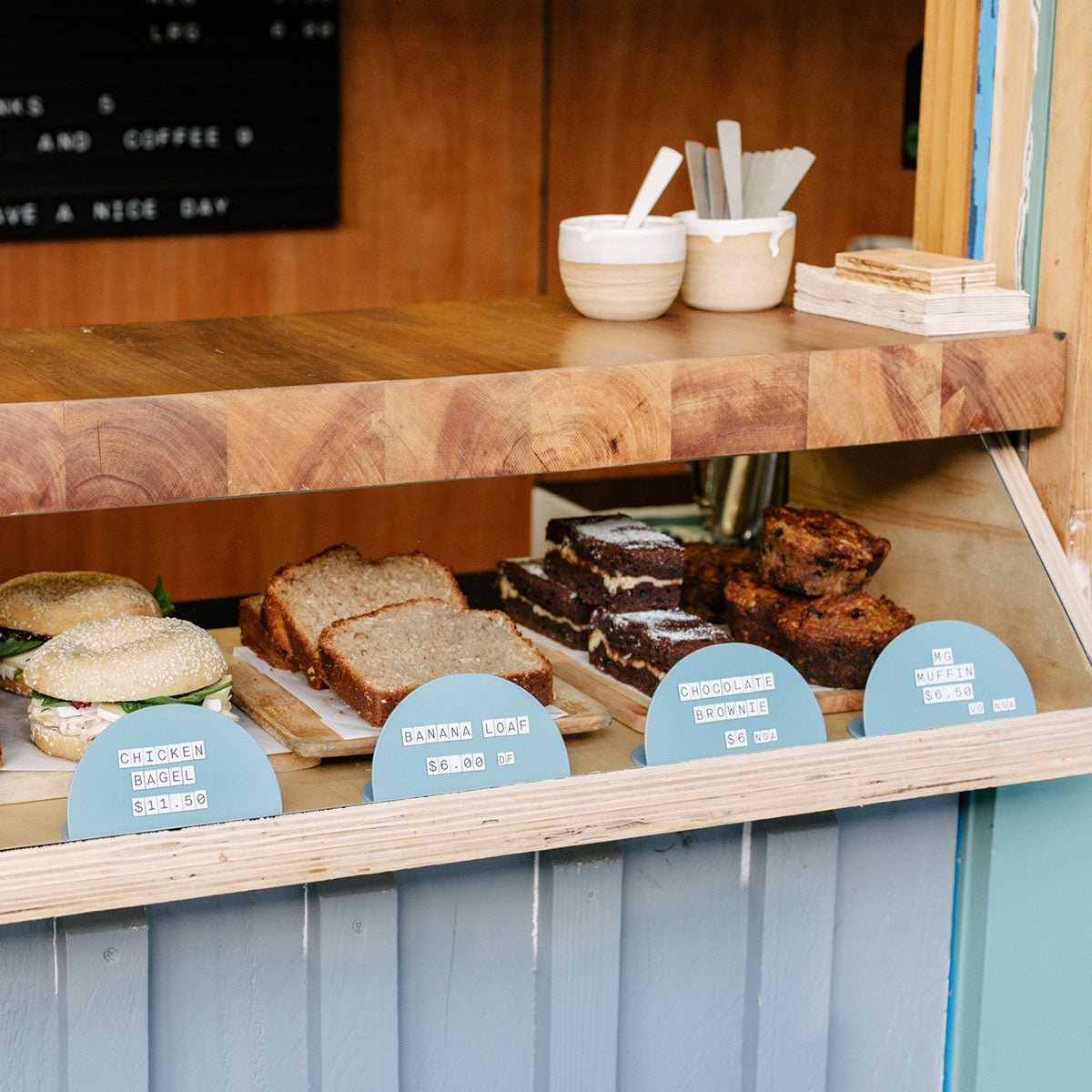 blue round counter signs in a display case in front of baking in a coffee kiosk