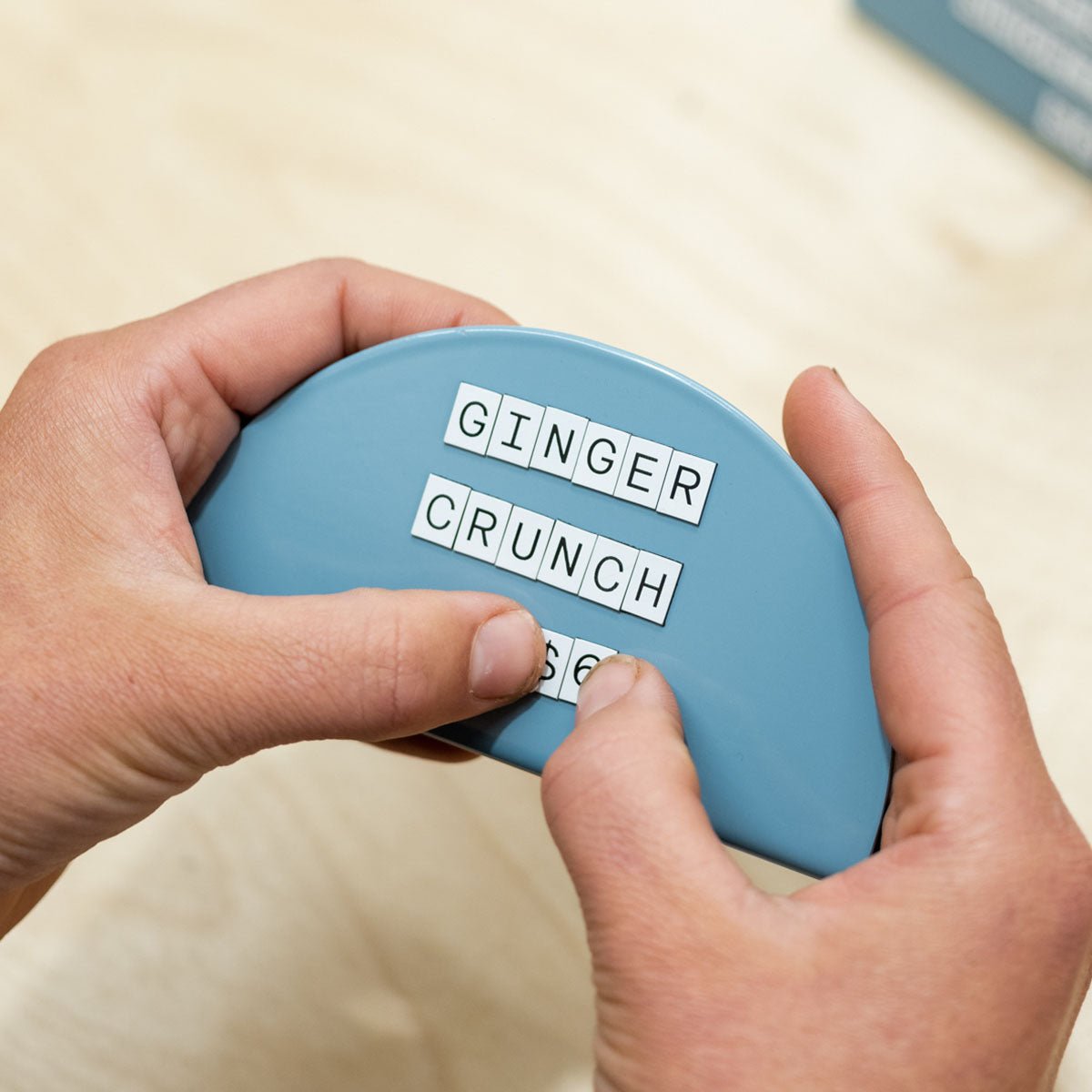 two hands adjusting white letters on blue round counter signs
