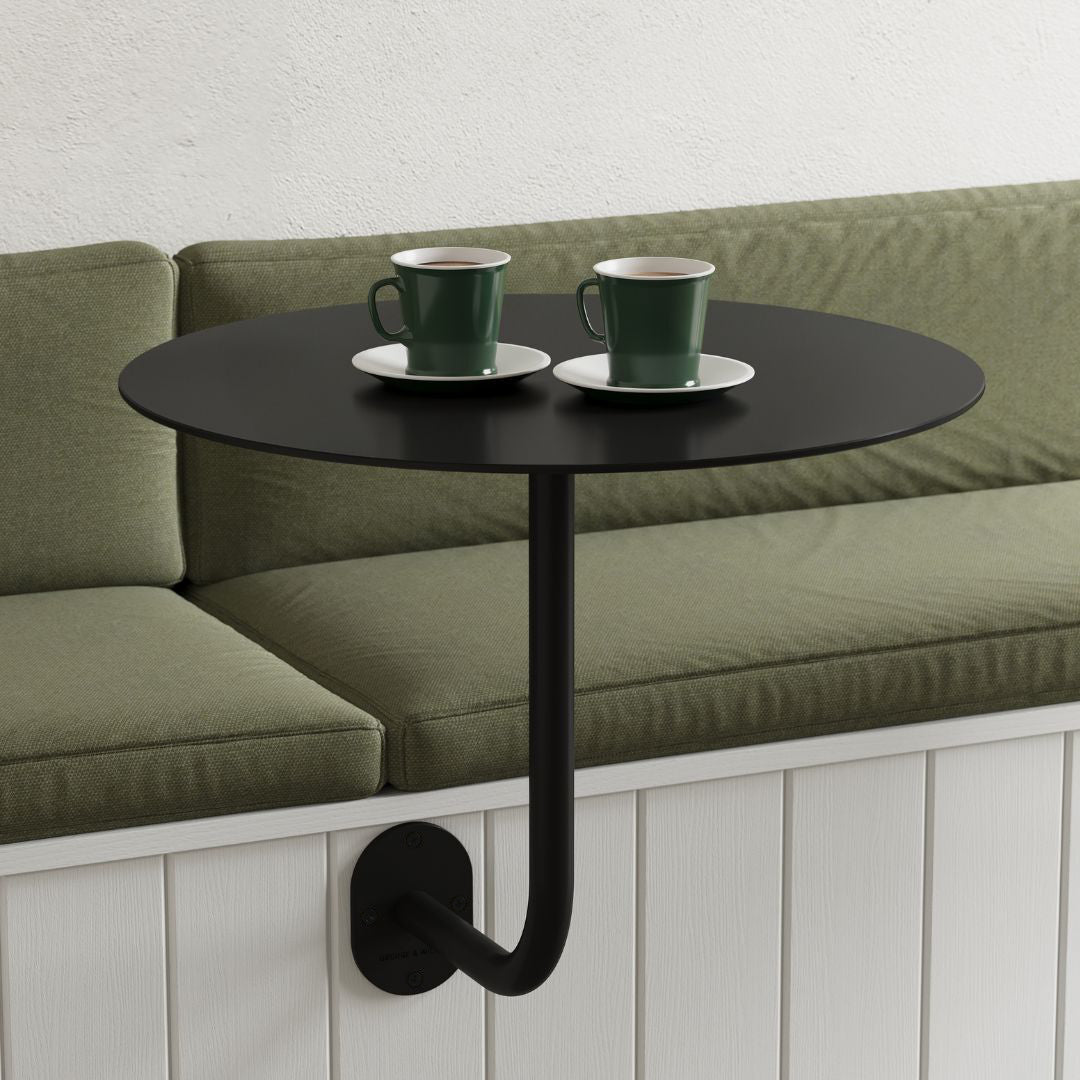 wall-mounted restaurant cafe table in black with round cafe table top, attached to booth seat
