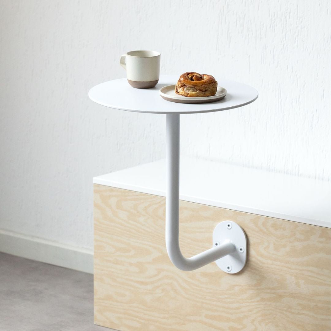 White wall-mounted cafe table with coffee and pastry on top, showcasing a compact cafe table