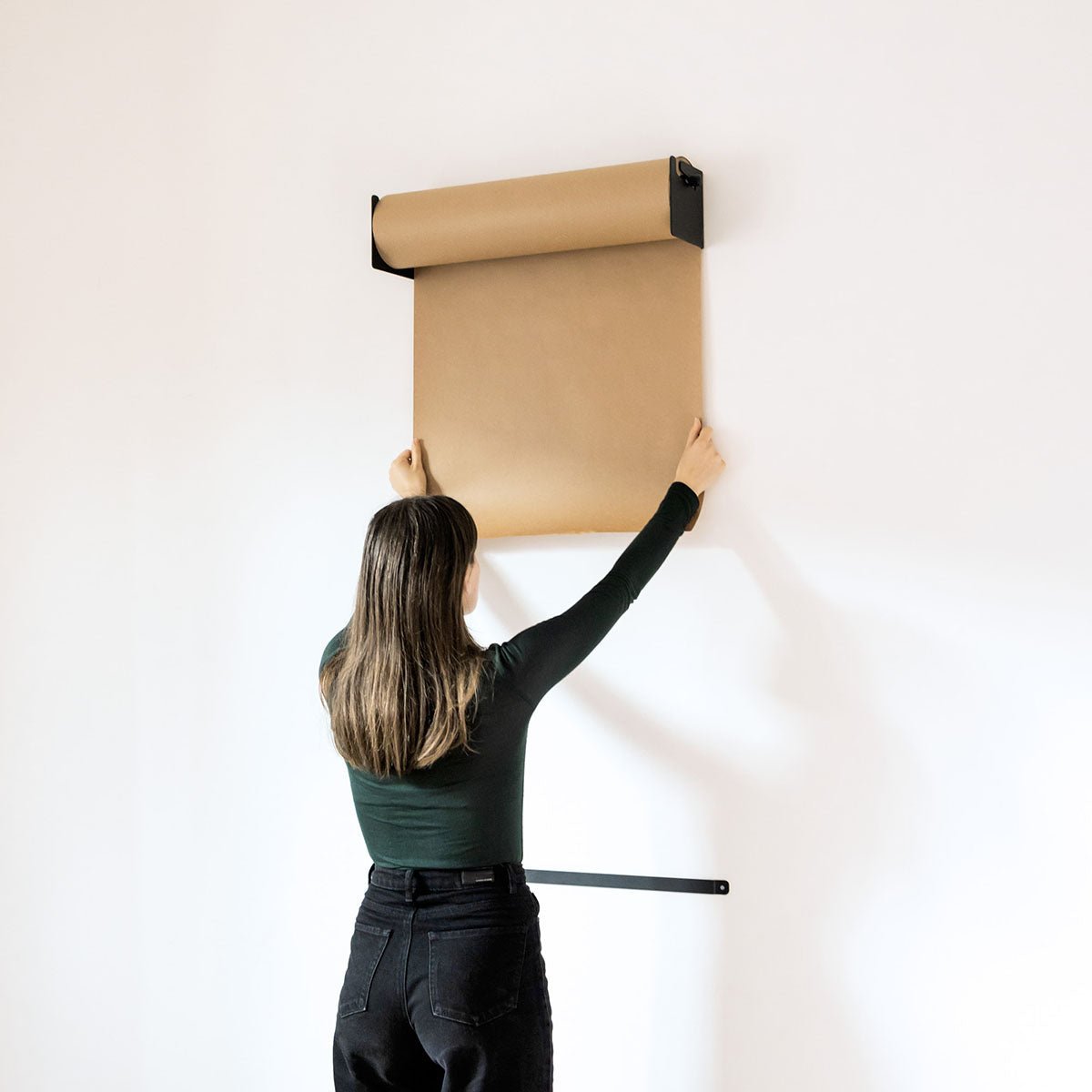 girl pulling down more kraft paper from the studio roller