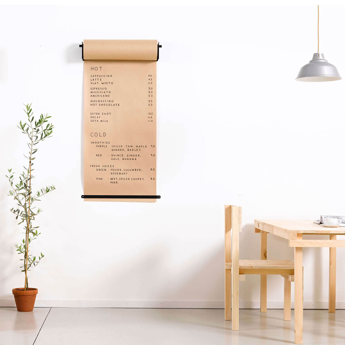 black studio roller installed on a wall beside a small craft room table and a plant.