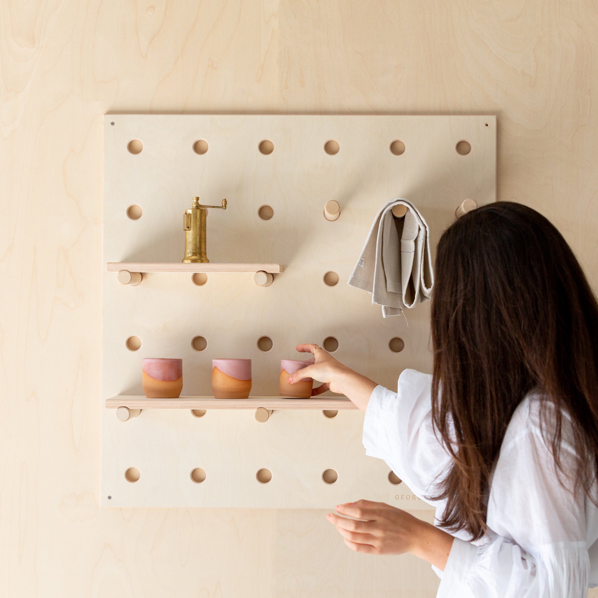 girl adjusting products held on a wooden pegboard shelf