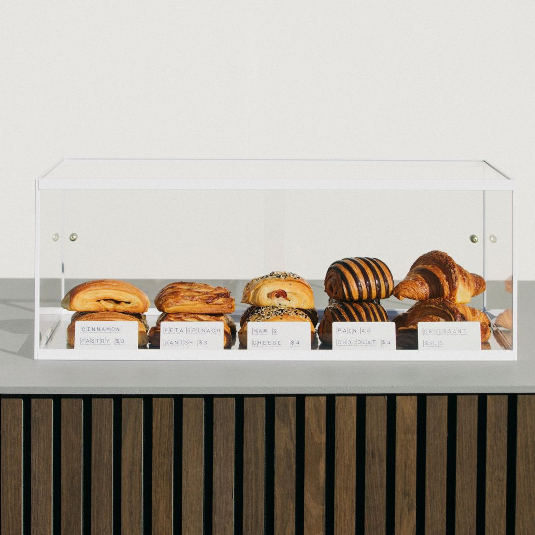 Countertop bakery display case with croissants and bagels in acrylic display cabinet