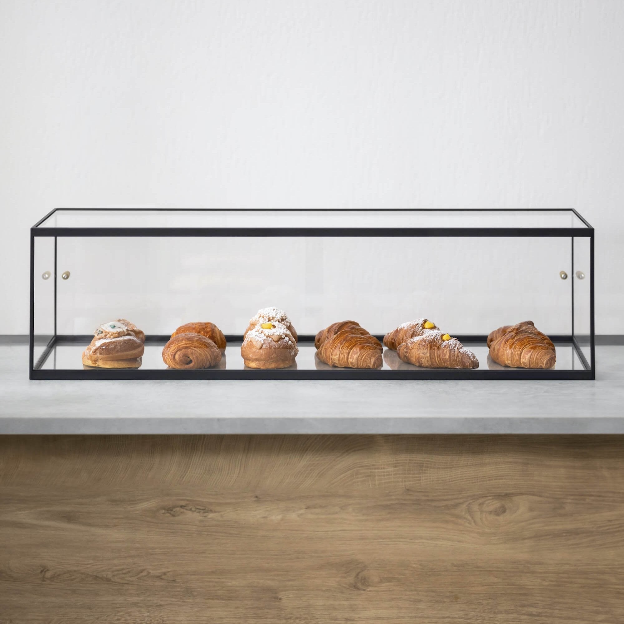 Long, acrylic bakery display case with one shelf of croissants against white background