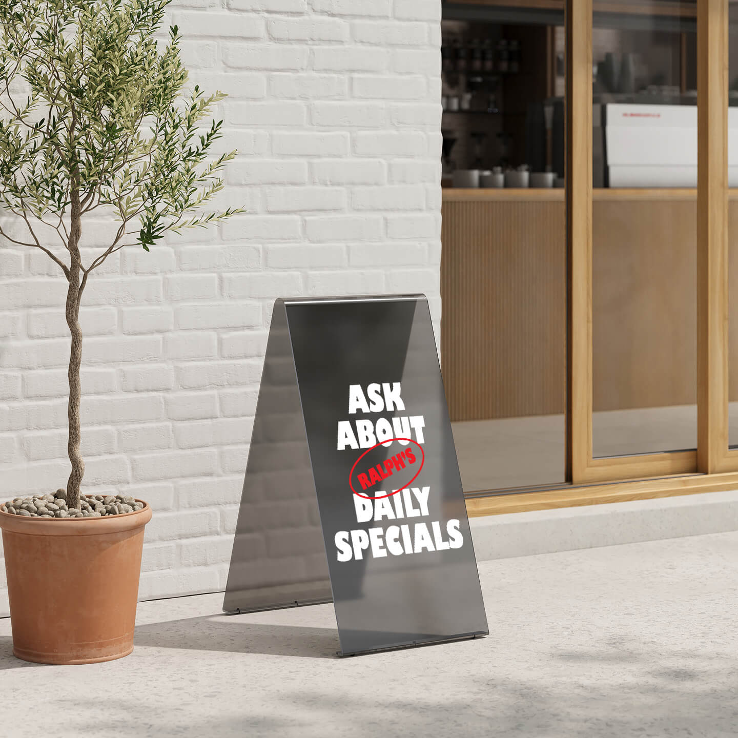 acrylic black a-frame sidewalk sign with custom branding applied outside a storefront beside a tree