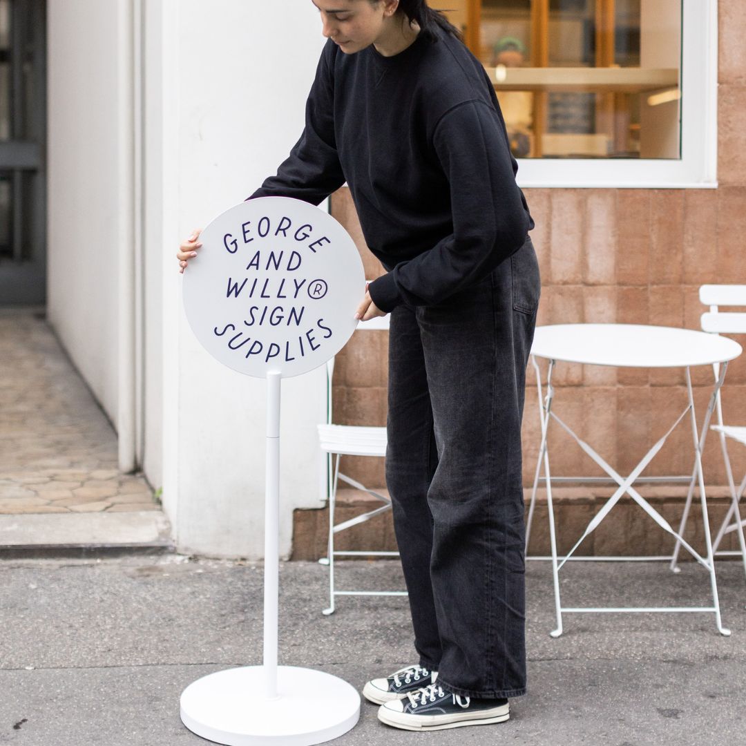 metal standing signs of advertising round sign with logo being placed on sidewalk by person