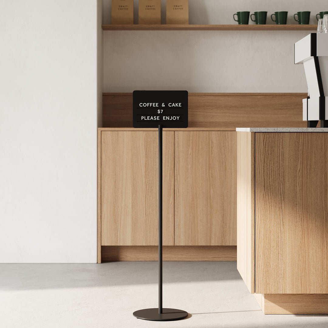 black standing rectangle sign beside a cafe countertop indoors
