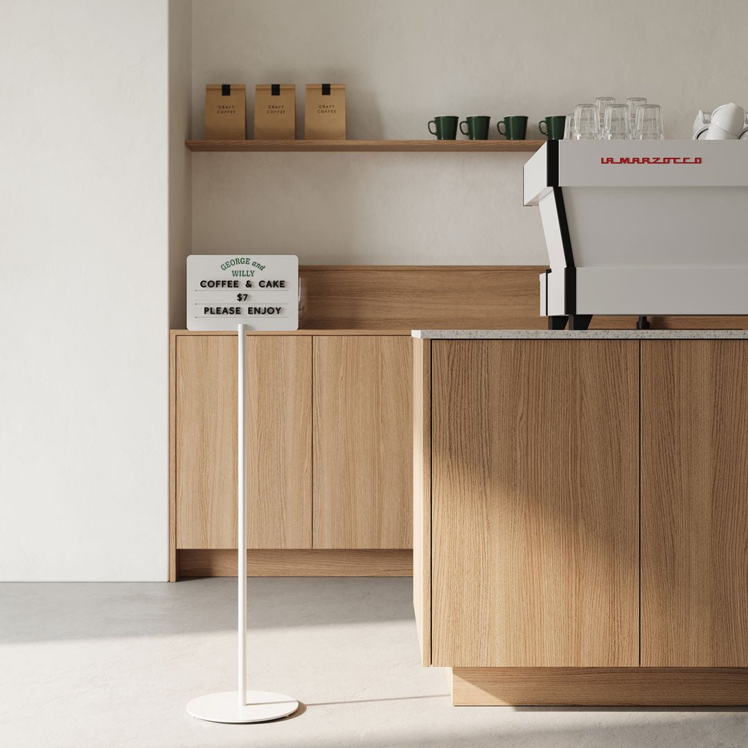 white standing rectangle sign beside a cafe countertop indoors
