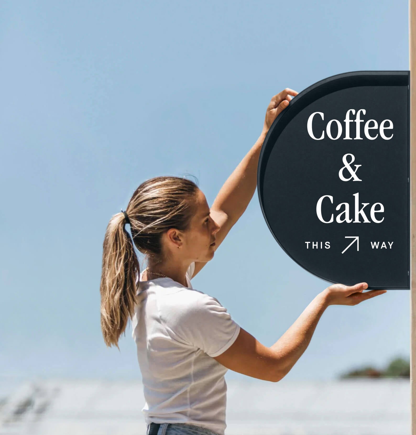 girl installing the half round wall sign with coffee logo branding applied to it
