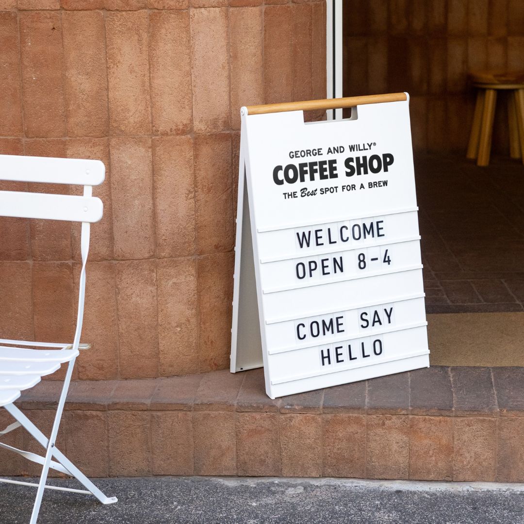 letter sidewalk sign outside a storefront facade on pavement