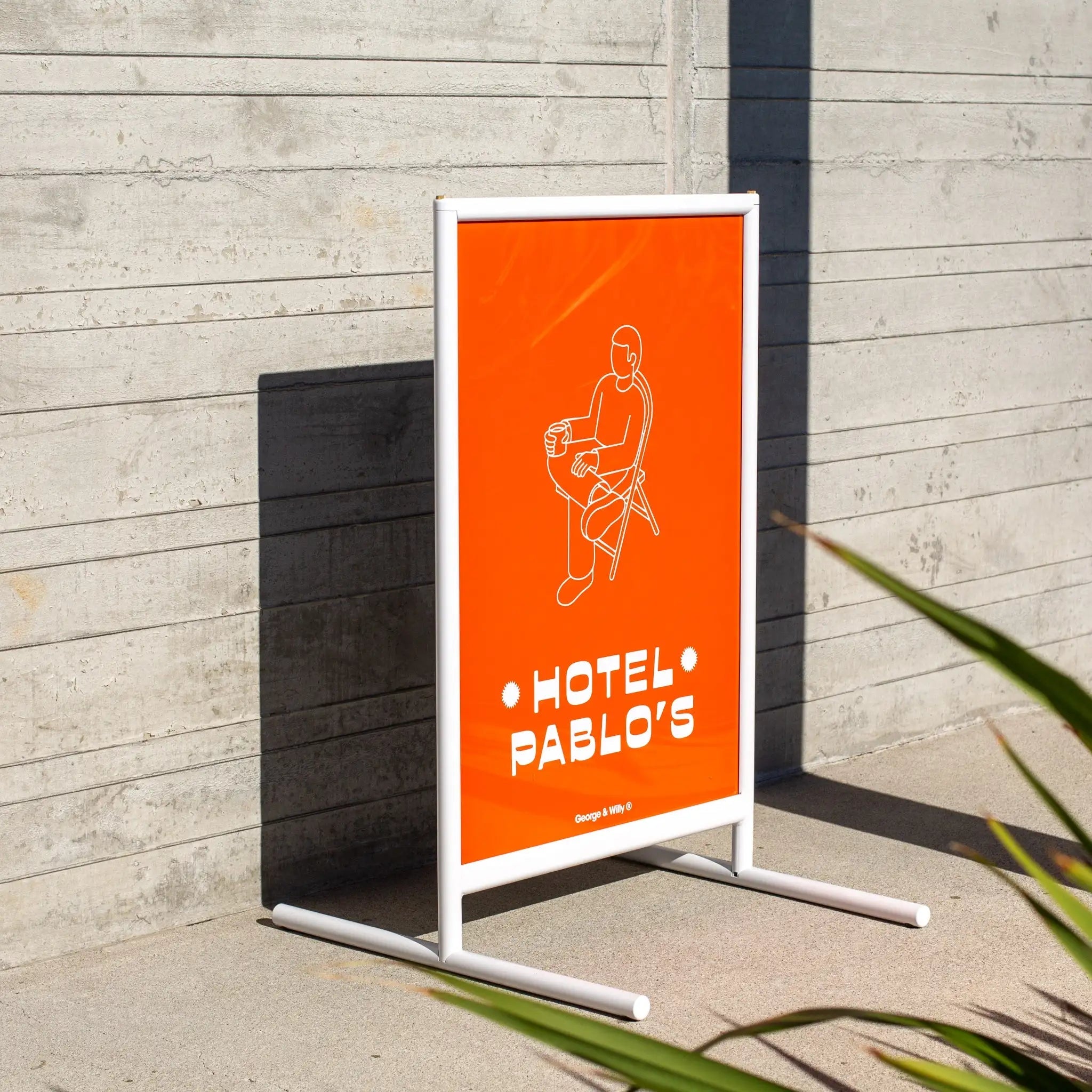 white framed poster sidewalk business sign outside against a wall on pavement with red poster inside