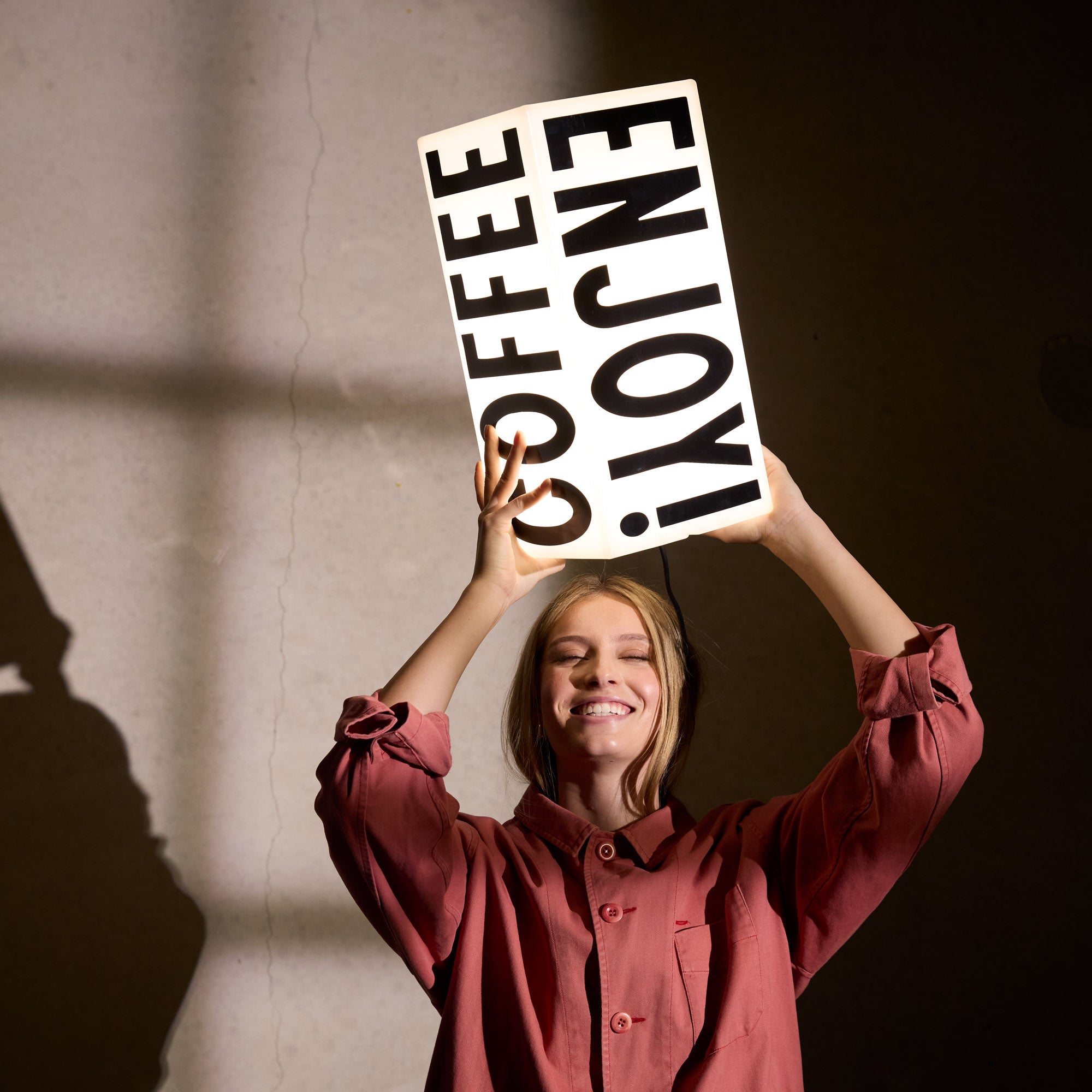 Young woman holding unmounted rectangular LED sign, showcasing lightweight design