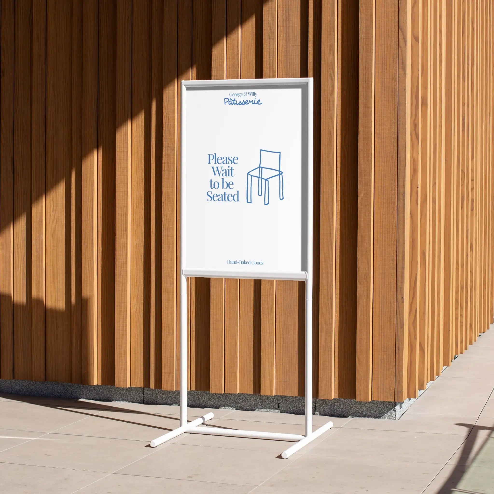 tall white poster sidewalk sign against a wooden wall