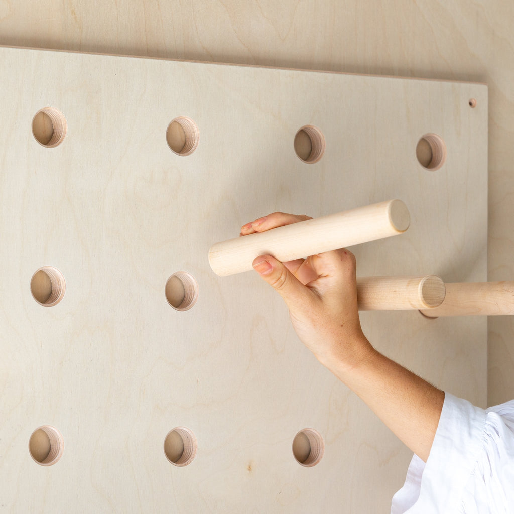 A plywood pegboard with dowel pegs and shelves designed for storing belongings or displaying products in a store