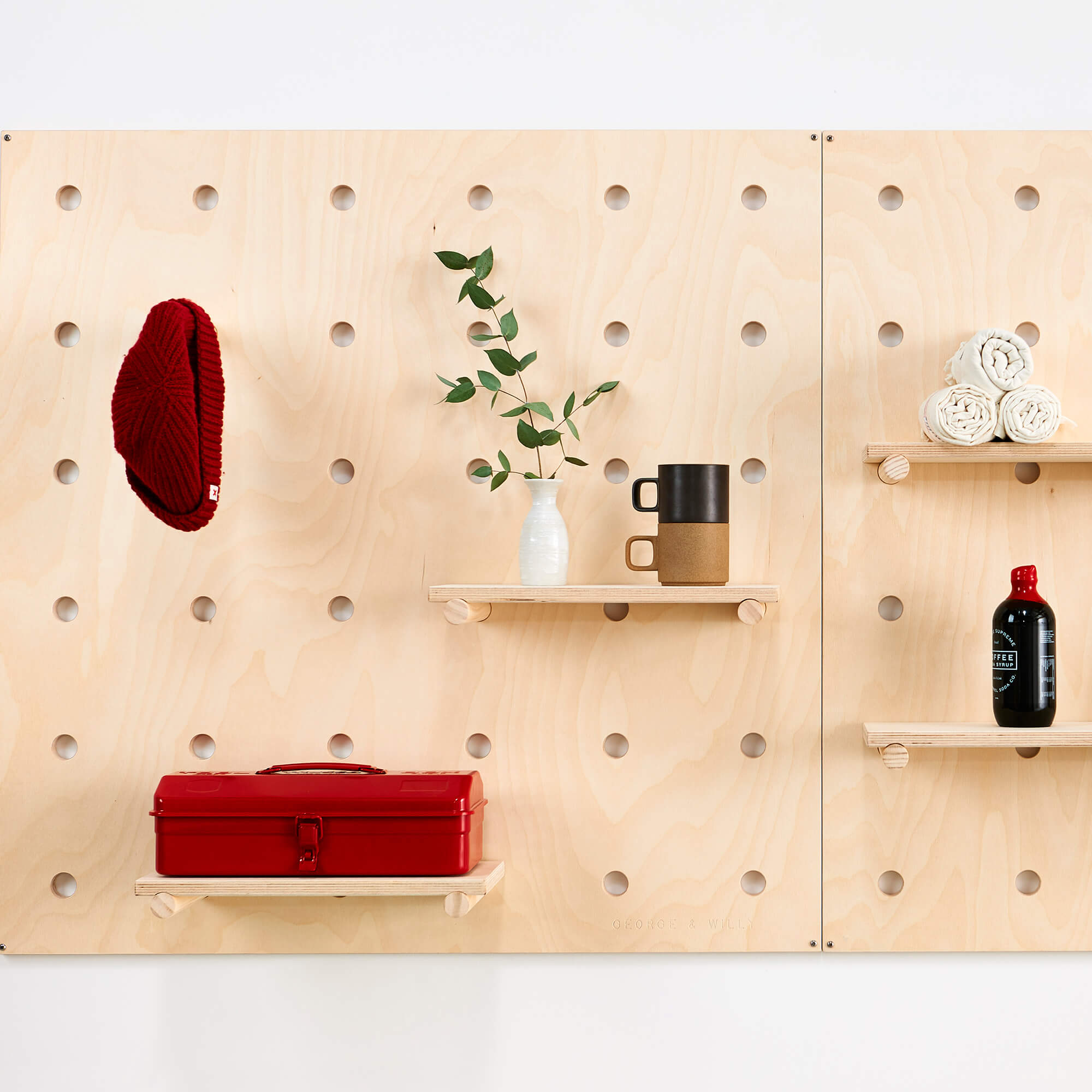 A wooden pegboard with dowel pegs and shelves designed for storing belongings or displaying products in a store