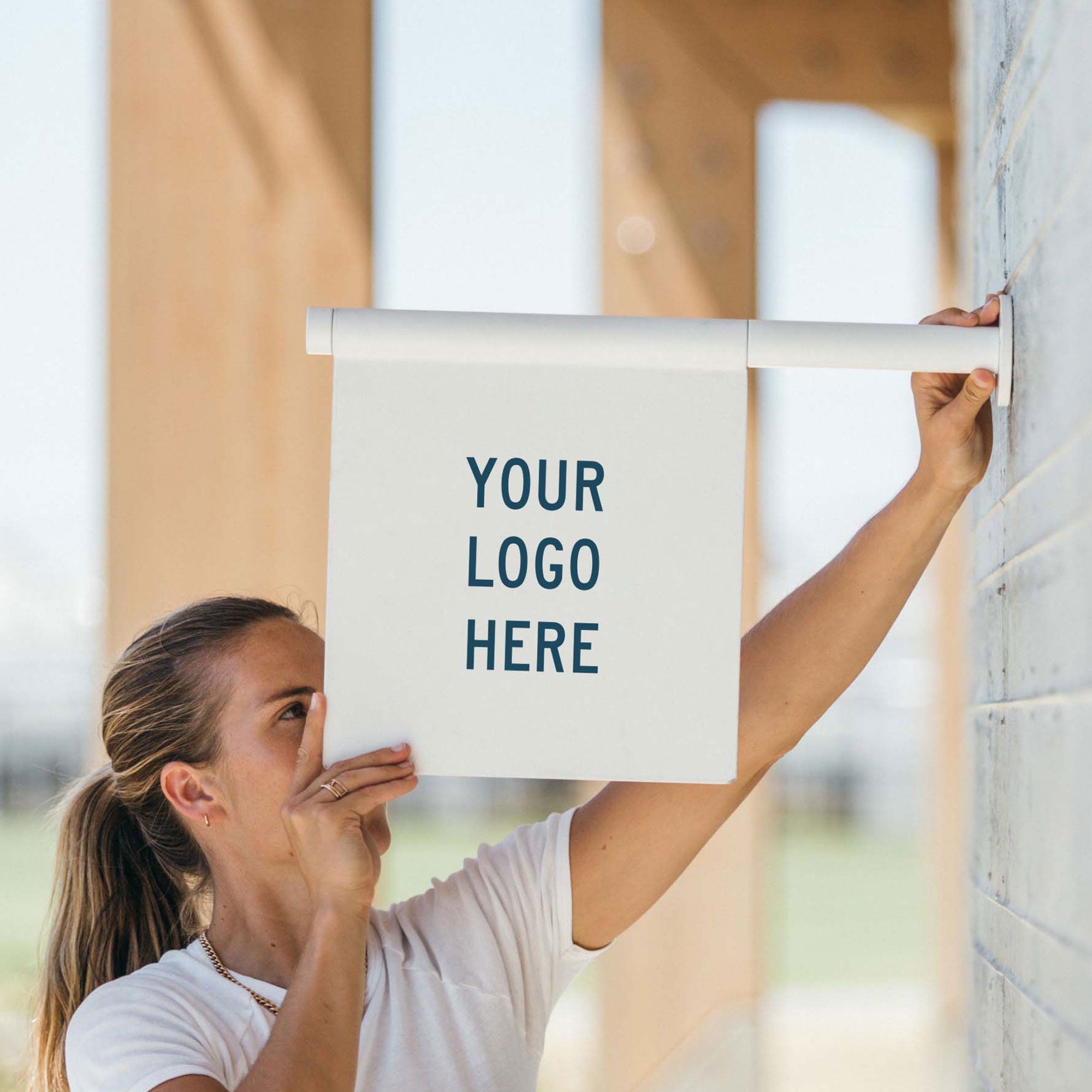 white wall hanging flag sign being installed by a girl on a cement wall