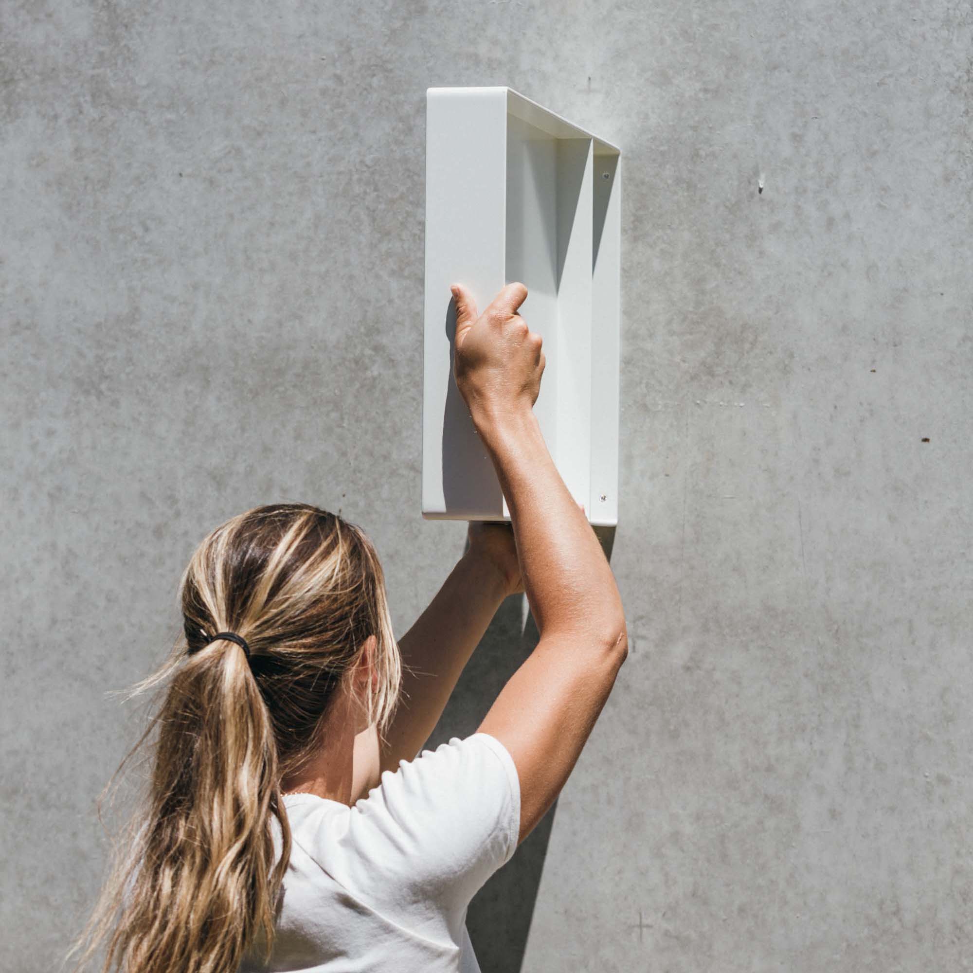 side shot of girl holding up square panel wall shop sign to show width